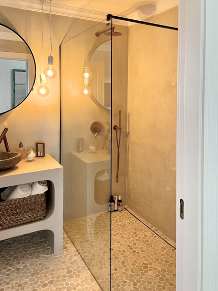 klimatyczne oświetlenie, betonowa łazienka z prysznicem walk-in, kamyczki na podłodze w hiszpańskim domu projektu purple pracownia